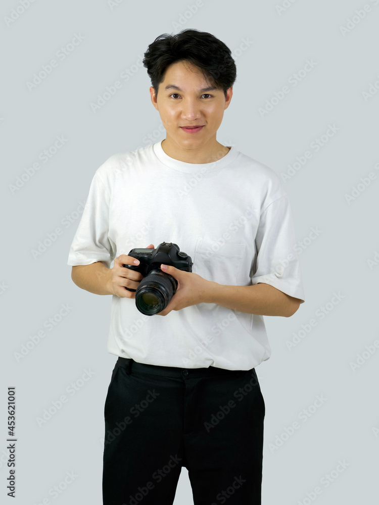 Asian photographer holding DSLR camera with both hand while standing in a white photography scene. The atmosphere in the photo studio.