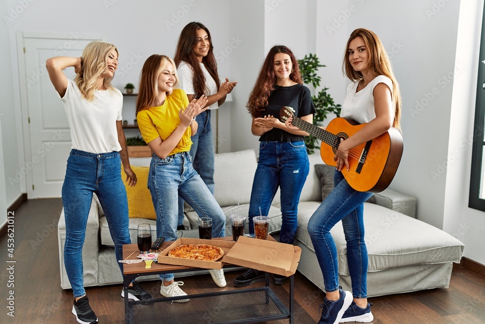 Obraz premium Group of young woman friends having party playing classical guitar at home.