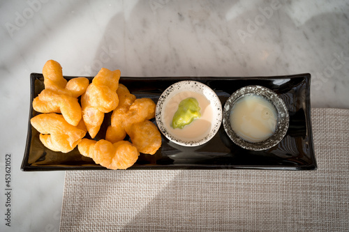 top view of Patonggo or deep-fried dough sticks on black dish with pandan and sweet condense milk dipping on table, Thai breakfast photo