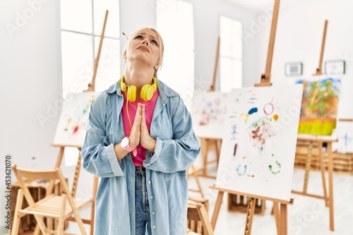 Fotografie Young caucasian girl at art studio begging and praying with hands together with hope expression on face very emotional and worried