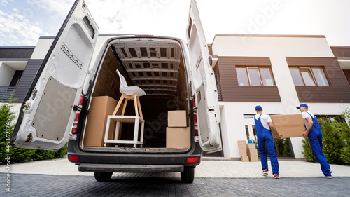 Two removal company workers unloading boxes and furniture from minibus photo