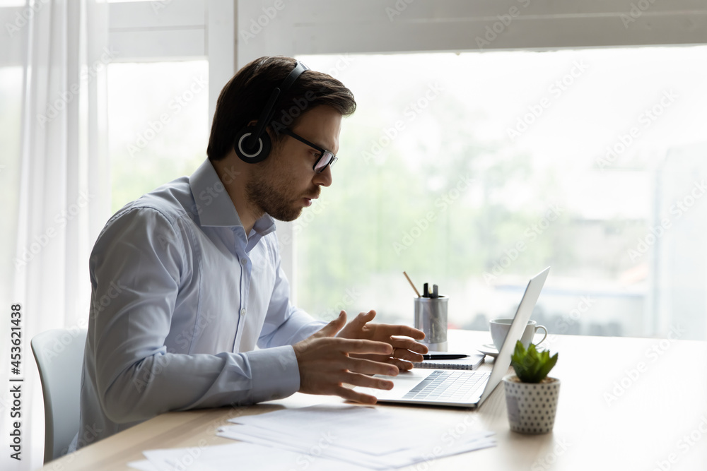 Foto de Annoyed office employee in headphones concerned about problems with  laptop. Angry computer user looking at screen, getting app or services  errors notice, shocking bad news, feeling stress at workplace do