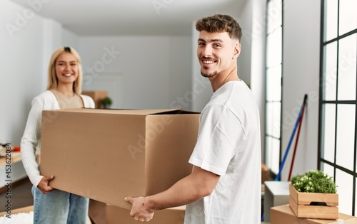 Young caucasian couple smiling happy holding cardboard boxes standing at new home. © Krakenimages.com