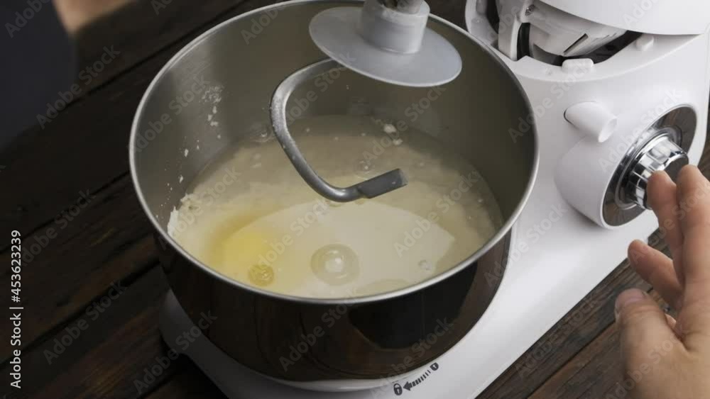 Slow motion. The chef lowers the kneading attachment into the bowl of the planetary mixer. Slow motion. The chef lowers the kneading attachment into the bowl of the planetary mixer.