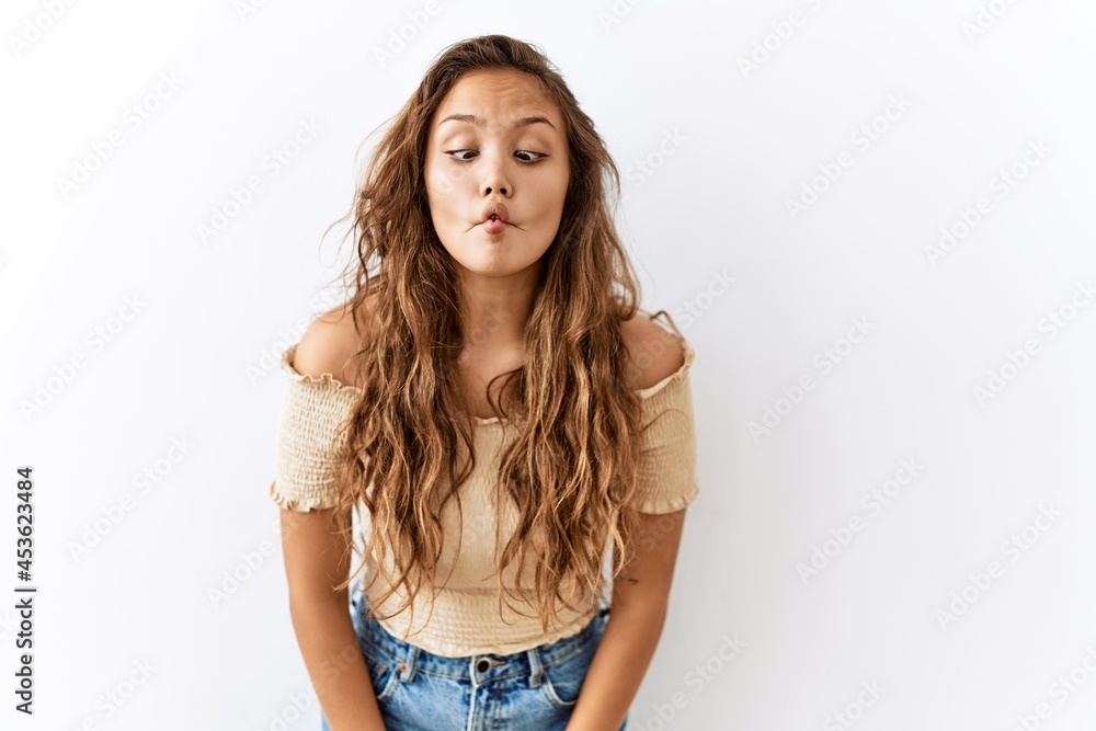 Beautiful hispanic woman standing over isolated while background making fish face with lips, crazy and comical gesture. funny expression. Beautiful hispanic woman standing over isolated while background making fish face with lips, crazy and comical gesture. funny expression.
