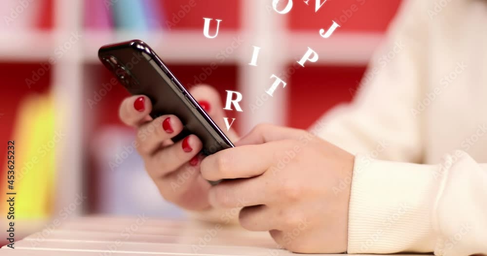 Hand of girl using smartphone in the living room at home, typing message. Animated letters of the alphabet fly out of the mobil phone.