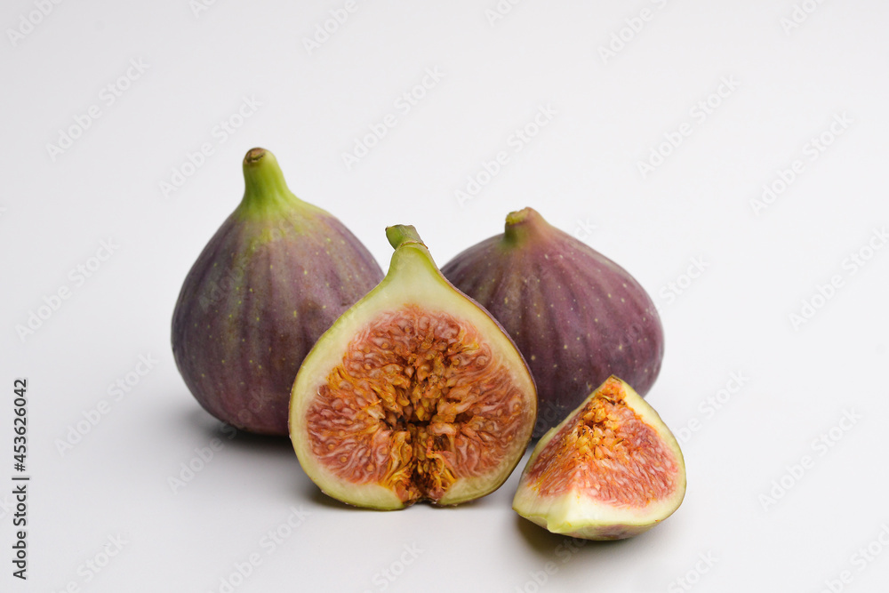 Isolated figs. Two whole and half figs isolated on a white background with a clipping path. purple fruit.