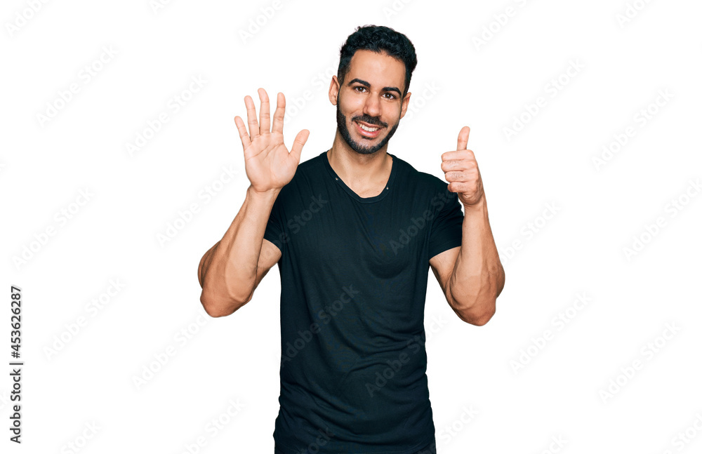 Fototapeta premium Hispanic man with beard wearing casual black t shirt showing and pointing up with fingers number six while smiling confident and happy.
