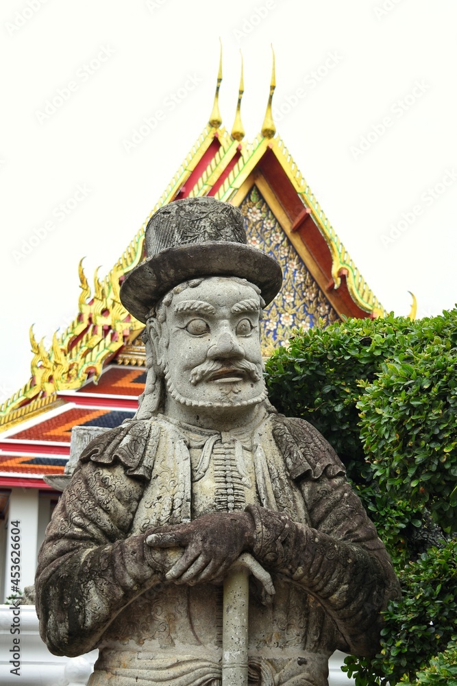 Obraz premium Chinese giants figure in european clothes beside a gate in Wat Pho also spelled Wat Po, is a Buddhist temple in Bangkok, Thailand.