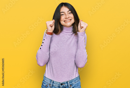 Young beautiful teen girl wearing turtleneck sweater excited for success with arms raised and eyes closed celebrating victory smiling. winner concept.