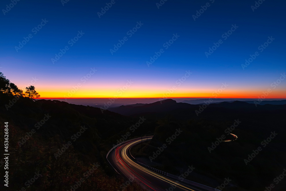 Sunrise scence of car light trail to the top with curve of road at Doi Inthanon National park in Chiang Mai Province, Thailand