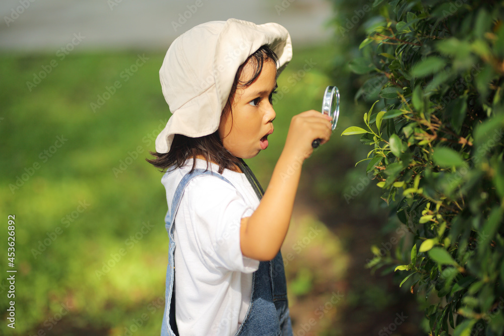 custom made wallpaper toronto digitalLittle kid girl asian wearing a white hat and jeans jumpsuit and xploring nature with a magnifying glass. Which increases the development and enhances outside the classroom learning skills concept.