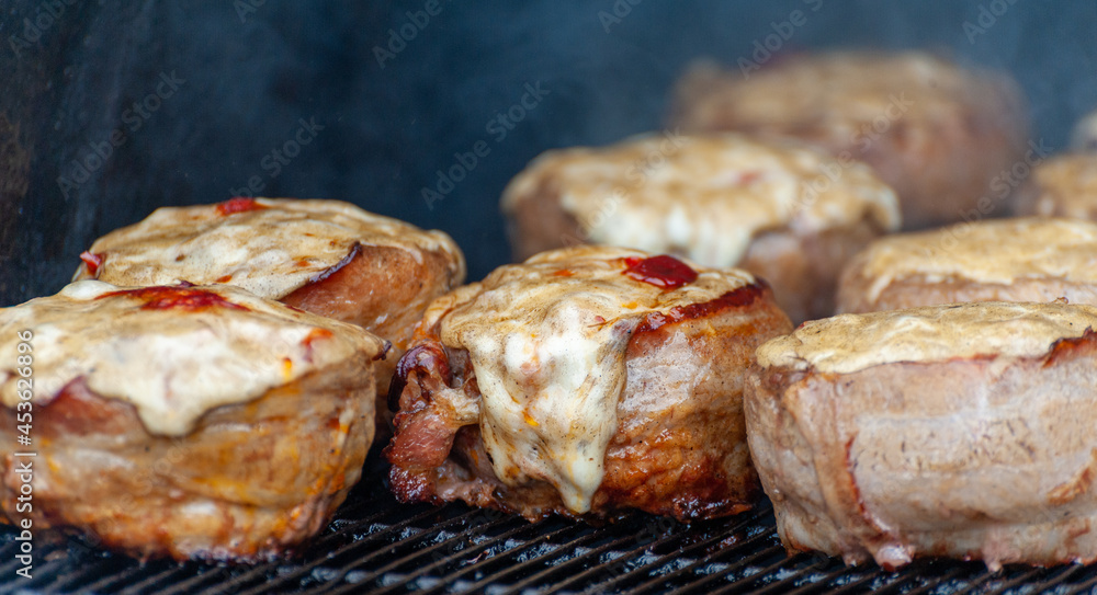 Cooking meatballs covered with bacon on the grill