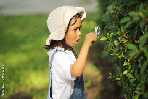 Wallpaper Mural Little kid girl asian wearing a white hat and jeans jumpsuit and xploring nature with a magnifying glass. Which increases the development and enhances outside the classroom learning skills concept. Torontodigital.ca