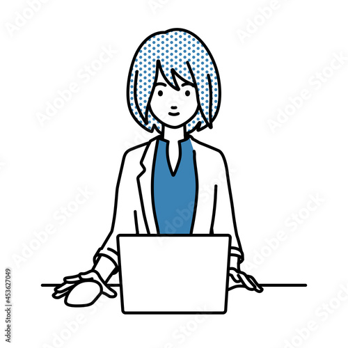 デスクで座ってPCを使っているジャケットの女性
