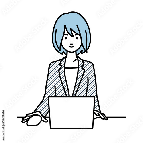 デスクで座ってPCを使っているスーツの女性