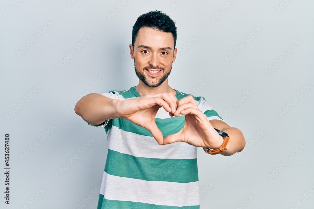 Young hispanic man wearing casual clothes smiling in love doing heart symbol shape with hands. romantic concept. Young hispanic man wearing casual clothes smiling in love doing heart symbol shape with hands. romantic concept.