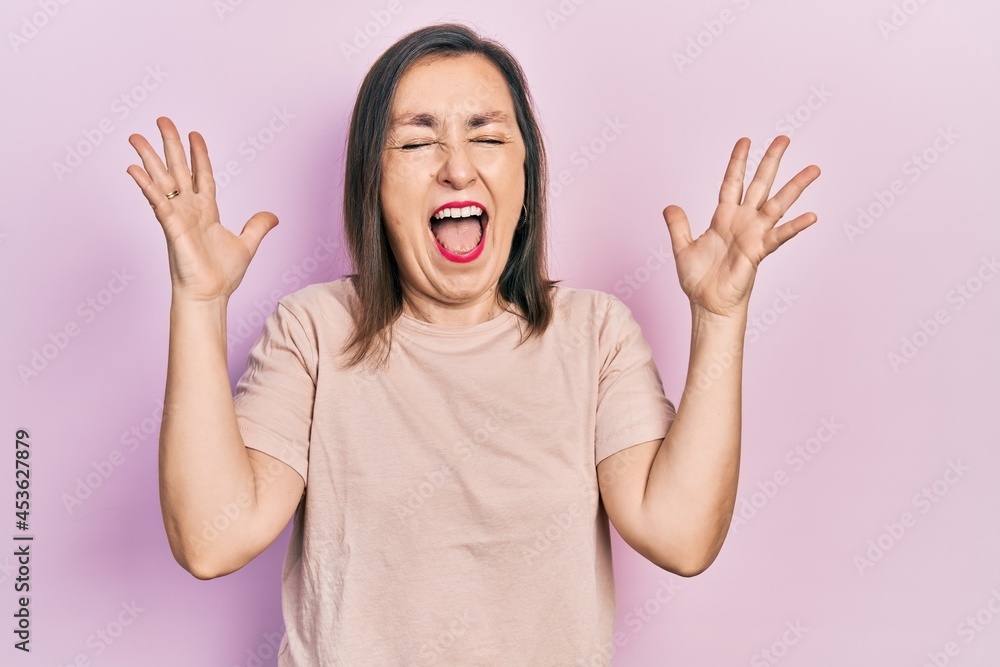 Middle age hispanic woman wearing casual clothes celebrating mad and crazy for success with arms raised and closed eyes screaming excited. winner concept Middle age hispanic woman wearing casual clothes celebrating mad and crazy for success with arms raised and closed eyes screaming excited. winner concept