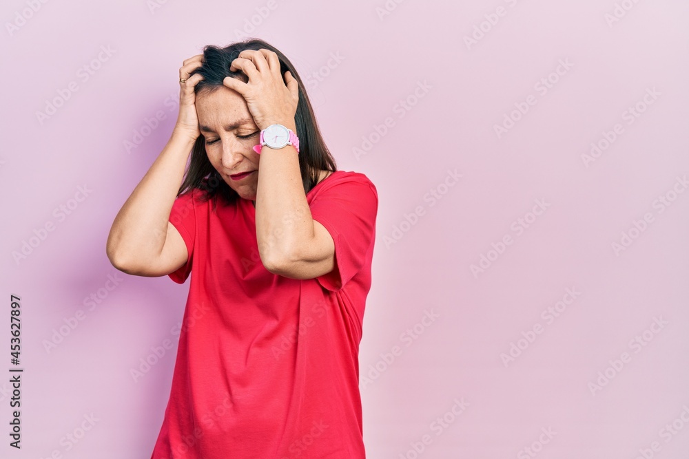 Middle age hispanic woman wearing casual clothes suffering from headache desperate and stressed because pain and migraine. hands on head. Middle age hispanic woman wearing casual clothes suffering from headache desperate and stressed because pain and migraine. hands on head.