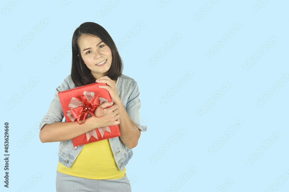 Portrait of happy young woman with red gift box hugging gesture on blue background. Present for birthday, valentine day, Christmas, New Year concept. Portrait of happy young woman with red gift box hugging gesture on blue background. Present for birthday, valentine day, Christmas, New Year concept.