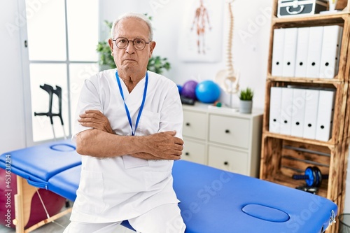 Senior physiotherapy man working at pain recovery clinic skeptic and nervous  disapproving expression on face with crossed arms. negative person.