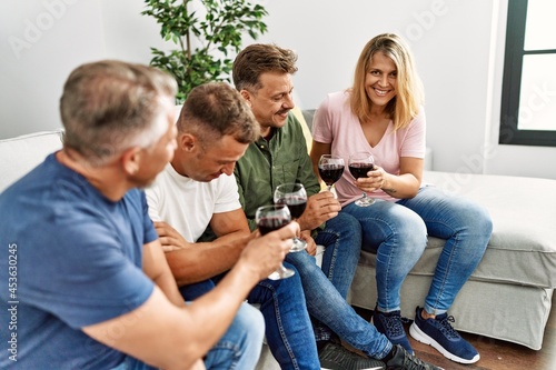 Group of middle age friends toasting with glass of wine at home.