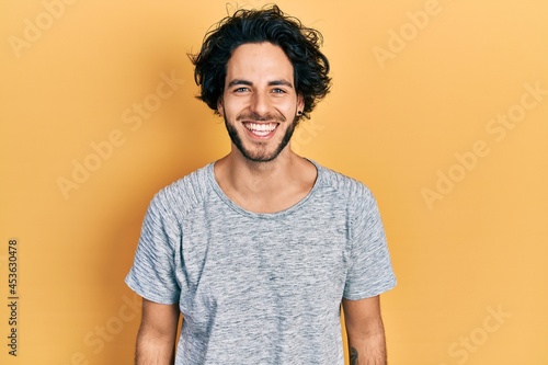 Handsome hispanic man wearing casual grey t shirt with a happy and cool smile on face. lucky person. © Krakenimages.com