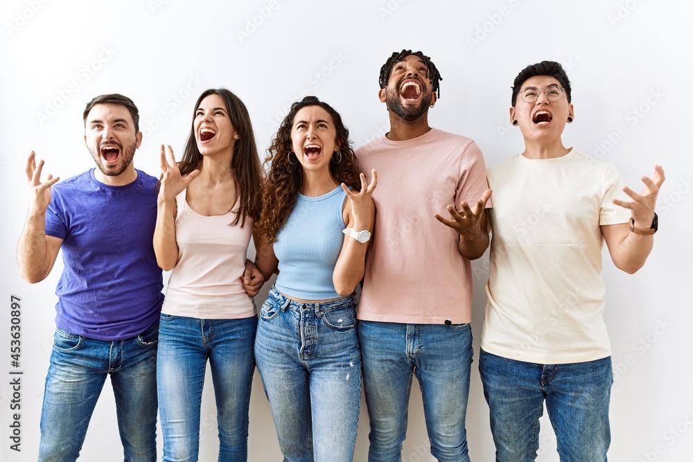 Group of young people standing together over isolated background crazy and mad shouting and yelling with aggressive expression and arms raised. frustration concept. Group of young people standing together over isolated background crazy and mad shouting and yelling with aggressive expression and arms raised. frustration concept.