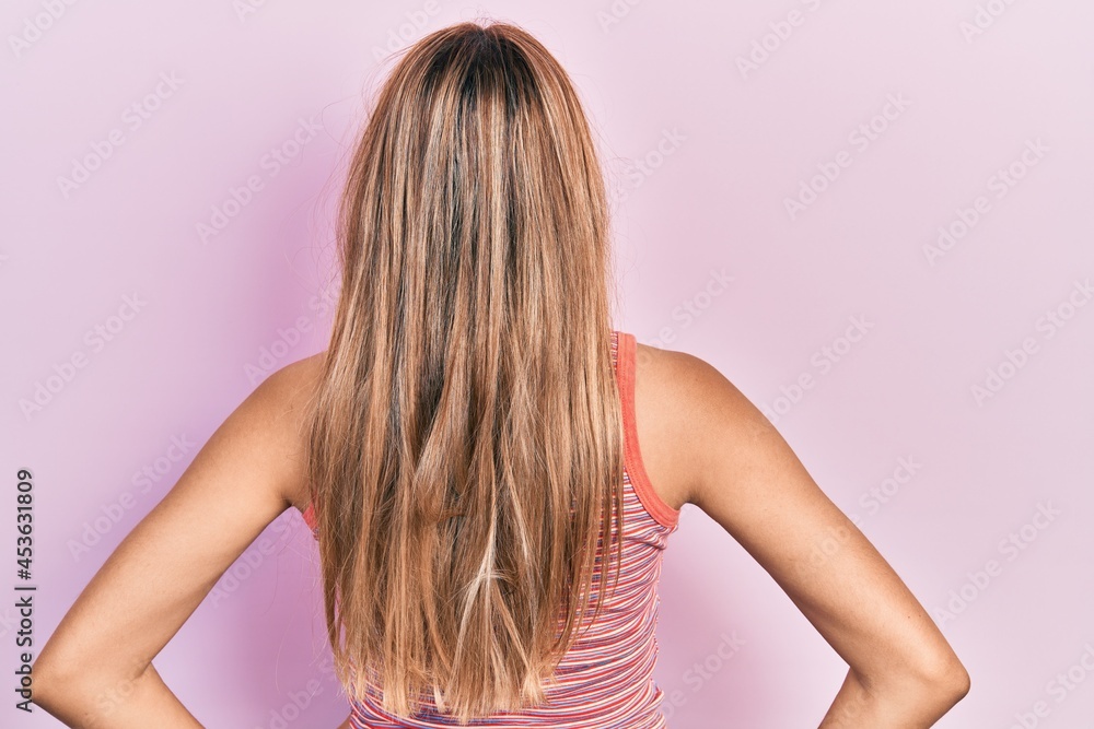 Beautiful hispanic woman wearing casual summer t shirt standing backwards looking away with arms on body Beautiful hispanic woman wearing casual summer t shirt standing backwards looking away with arms on body