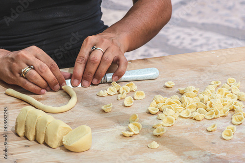 Fototapeta Naklejka Na Ścianę i Meble -  Local woman preparing in the street of Bari old town orecchiette or orecchietta, made with durum wheat and water, handmade pasta typical of Puglia or Apulia, a region of Southern Italy, close up