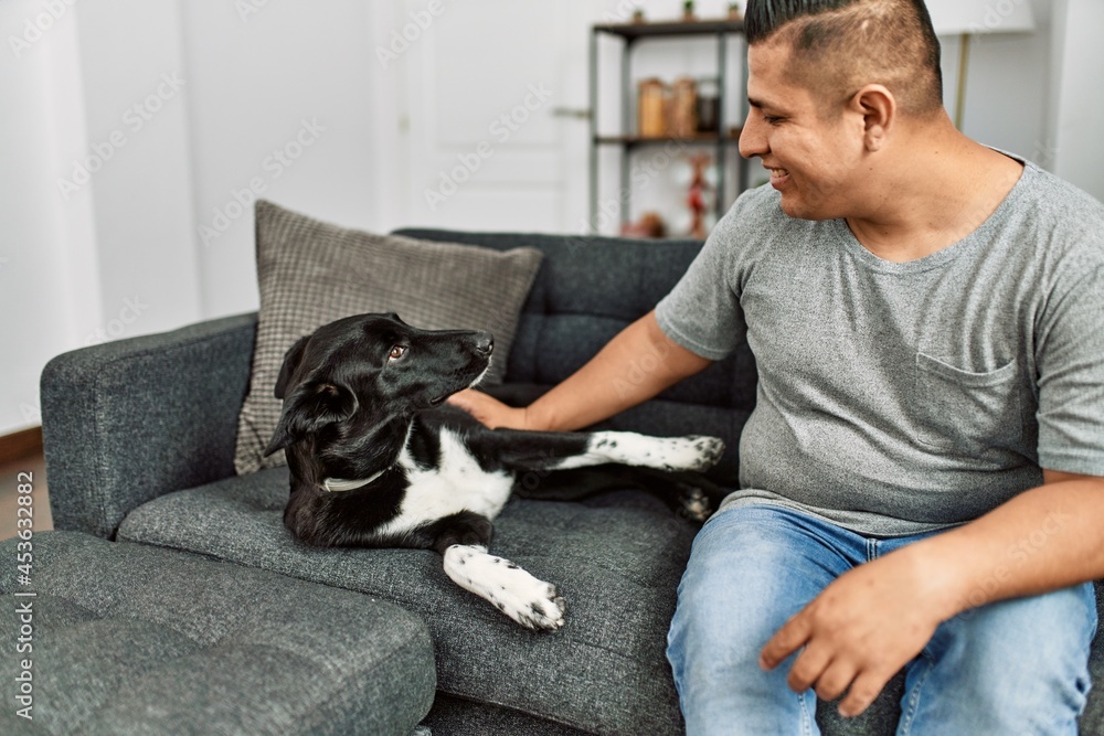 Young hispanic man smiling happy sitting on the sofa with dog at home. Young hispanic man smiling happy sitting on the sofa with dog at home.