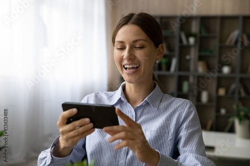 Close up overjoyed woman laughing, looking at smartphone screen, positive excited young female having fun with device, watching funny movie or reading news in social networks, making video call