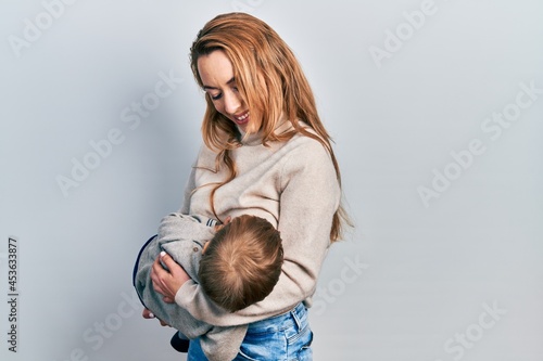 Young caucasian woman holding and hugging her son breastfeeding him, maternity lactation