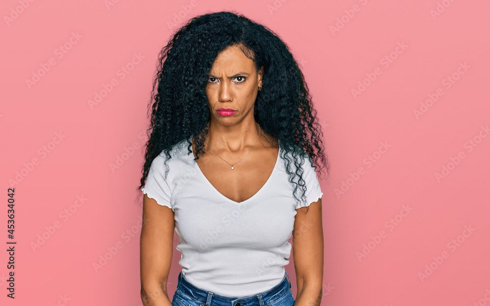 Middle age african american woman wearing casual white t shirt skeptic and nervous, frowning upset because of problem. negative person. Middle age african american woman wearing casual white t shirt skeptic and nervous, frowning upset because of problem. negative person.