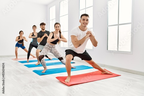 Group of young hispanic people smiling happy training yoga at sport center.