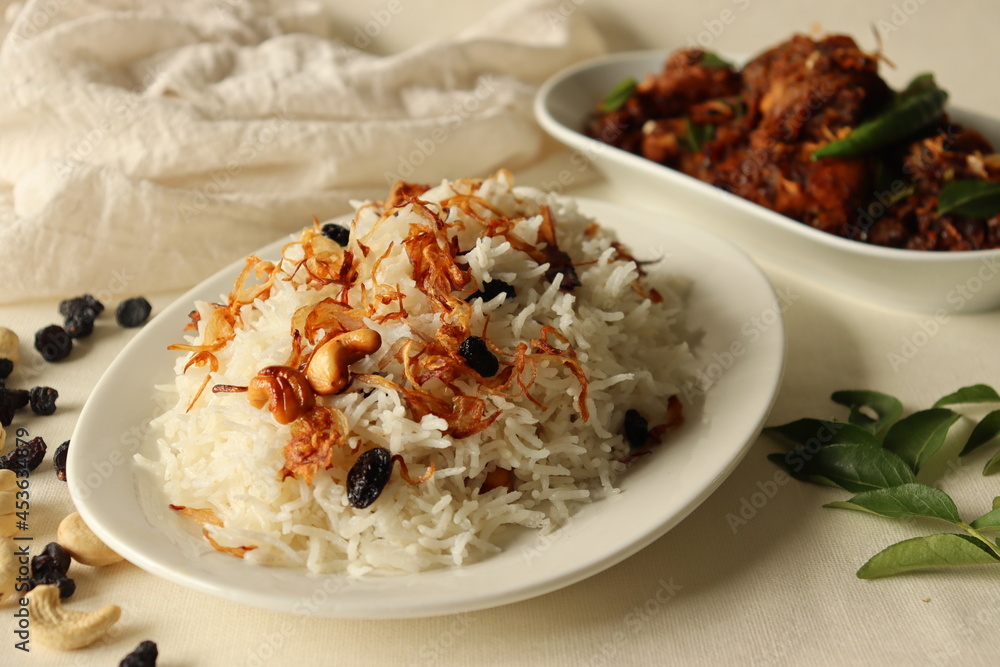 Rice dish made of Basmati rice, ghee and spices and garnished with fried onions served with Kerala style spicy chicken roast. Rice dish made of Basmati rice, ghee and spices and garnished with fried onions served with Kerala style spicy chicken roast.