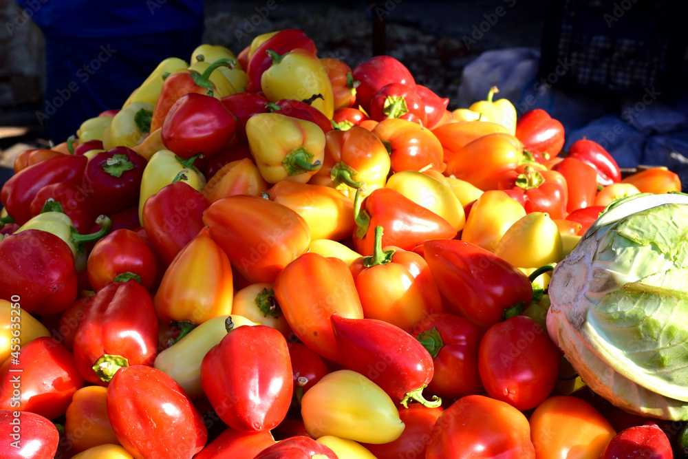 There is a mountain of ripe sweet bell peppers on the shelves of the peasant market.