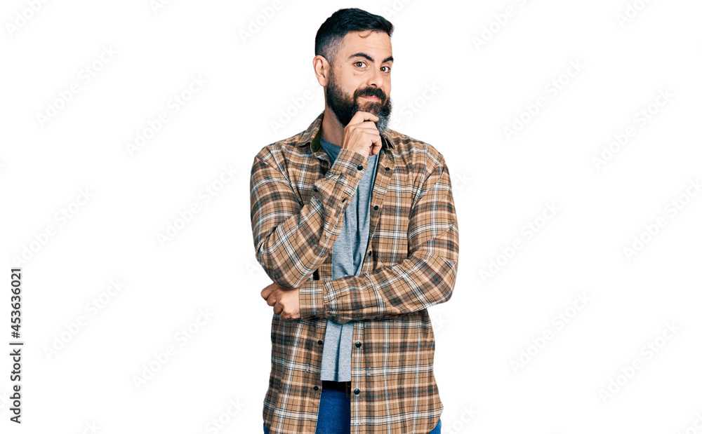 Hispanic man with beard wearing casual shirt looking confident at the camera with smile with crossed arms and hand raised on chin. thinking positive. Hispanic man with beard wearing casual shirt looking confident at the camera with smile with crossed arms and hand raised on chin. thinking positive.
