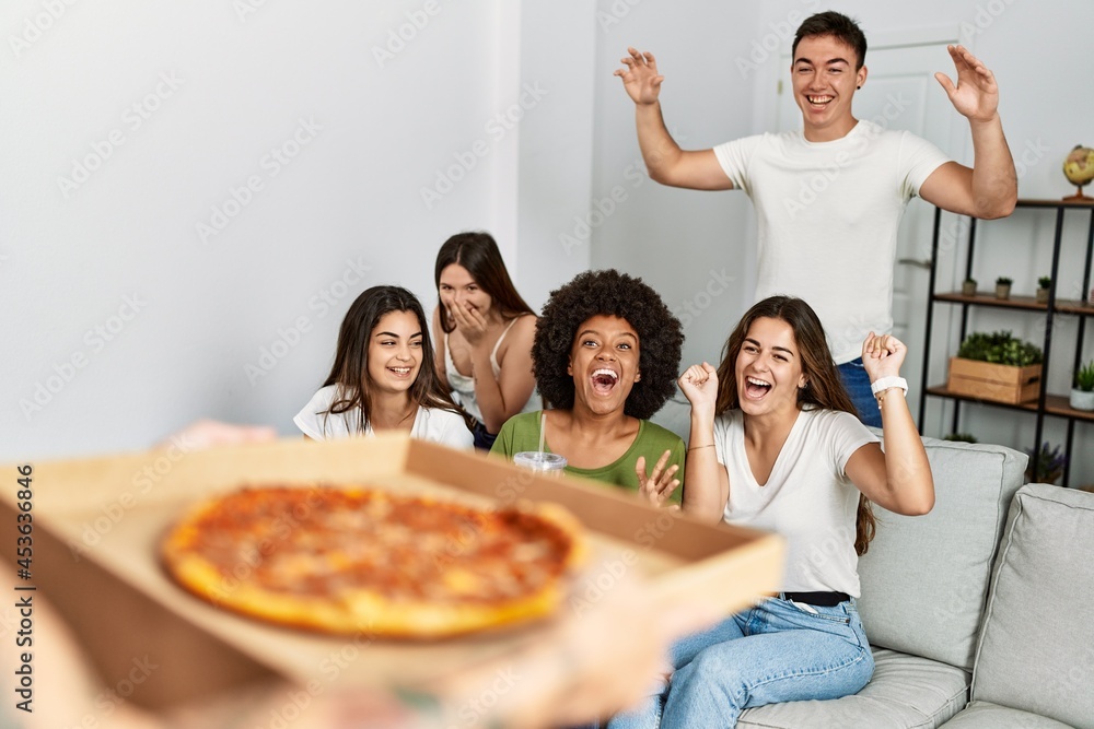 Group of young friends smiling happy waiting for italian pizza at home.