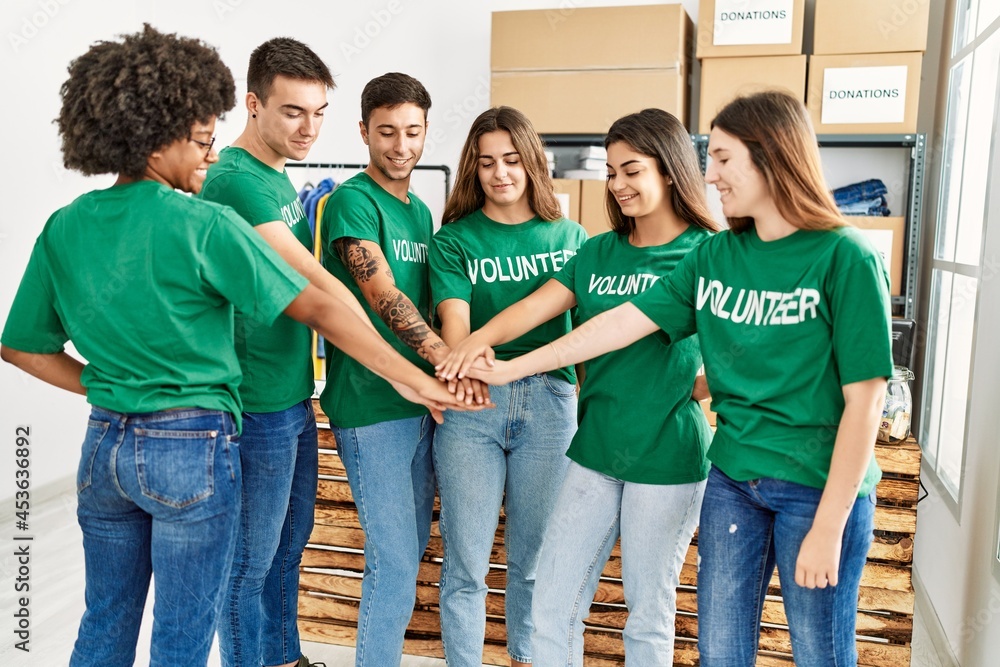 Fototapeta premium Group of young volunteers smiing happy with hands together at charity center.