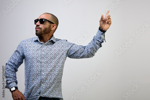 Cool, self-confident Latino man with a beard and a shirt, pointing his finger up, isolated on a white background photo