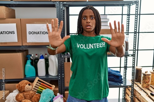 Young african american woman working wearing volunteer t shirt at donations stand doing stop gesture with hands palms  angry and frustration expression