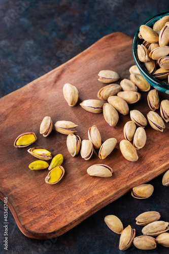 Roasted pistachios nuts. Fried and salty pistachios on wooden background. Close-up