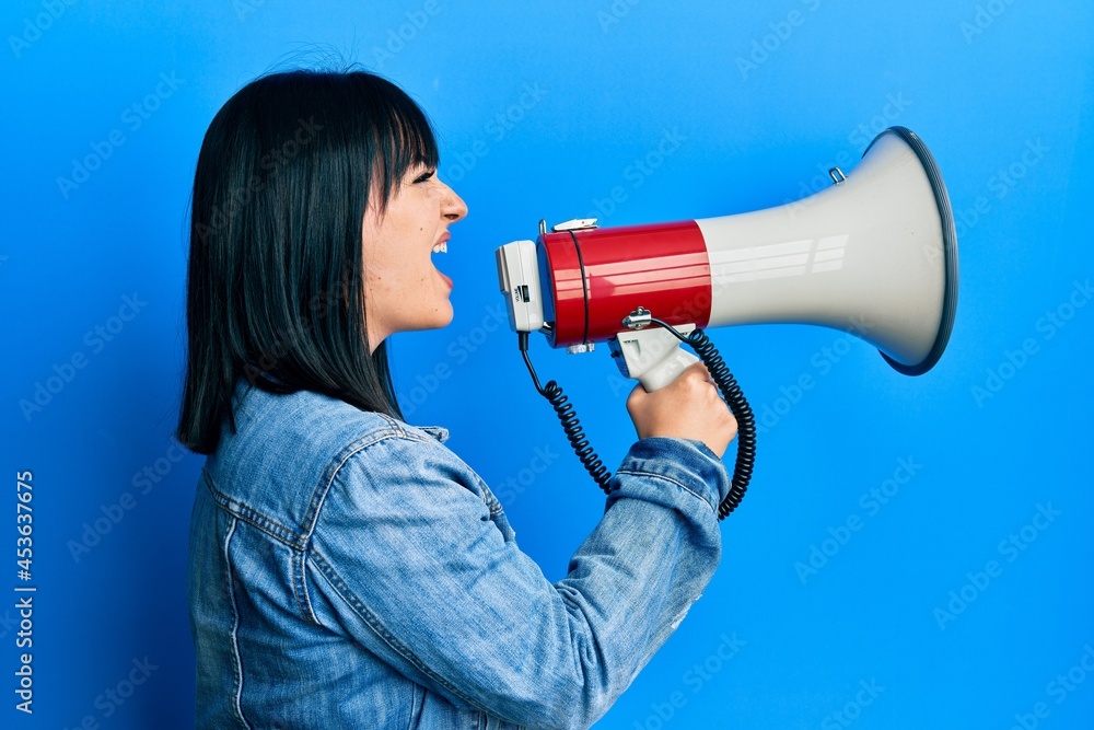 Young plus size woman shouting using megaphone Young plus size woman shouting using megaphone