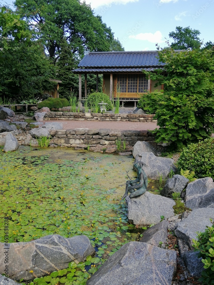 St. Petersburg, Russia - July 4, 2021. Peter the Great Botanical Garden. A tea house in the Japanese garden of the architect and designer Yamada Midori near an artificial pond on a sunny summer day. St. Petersburg, Russia - July 4, 2021. Peter the Great Botanical Garden. A tea house in the Japanese garden of the architect and designer Yamada Midori near an artificial pond on a sunny summer day.