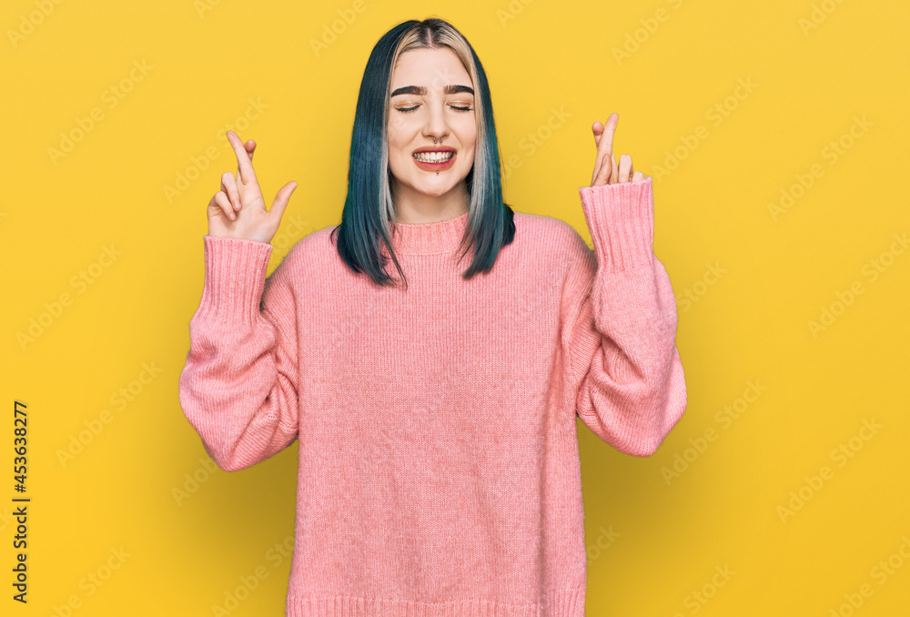 Young modern girl wearing pink wool winter sweater gesturing finger crossed smiling with hope and eyes closed. luck and superstitious concept. Young modern girl wearing pink wool winter sweater gesturing finger crossed smiling with hope and eyes closed. luck and superstitious concept.