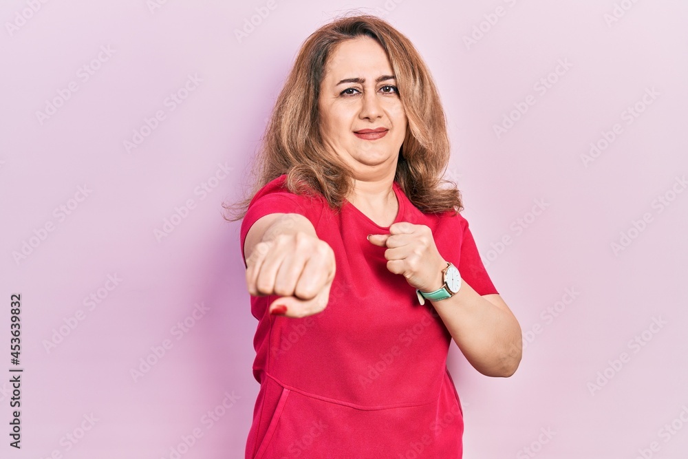 Middle age caucasian woman wearing casual clothes punching fist to fight, aggressive and angry attack, threat and violence Middle age caucasian woman wearing casual clothes punching fist to fight, aggressive and angry attack, threat and violence