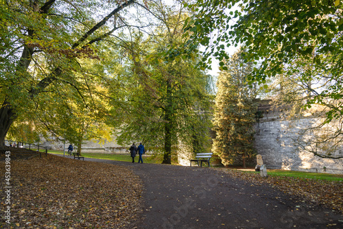 Outdoor scenery of walking way along Jeker canal and historical city wall at Monseigneur Nolenspark, city public park, in Autumn season, in Maastricht, Netherlands during evening sunset time. 