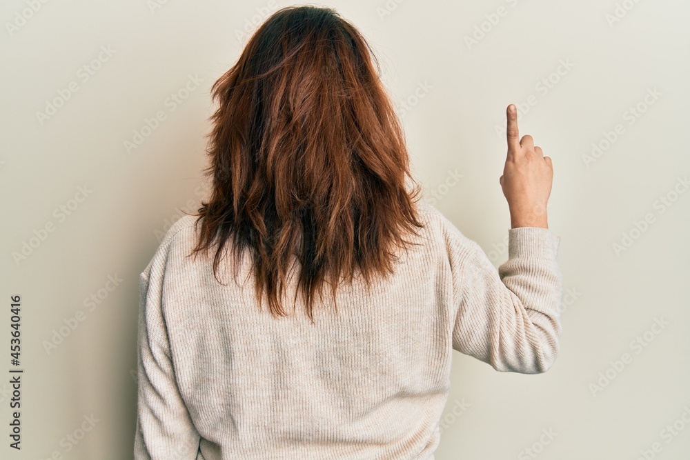 Young caucasian woman wearing casual clothes posing backwards pointing ahead with finger hand Young caucasian woman wearing casual clothes posing backwards pointing ahead with finger hand
