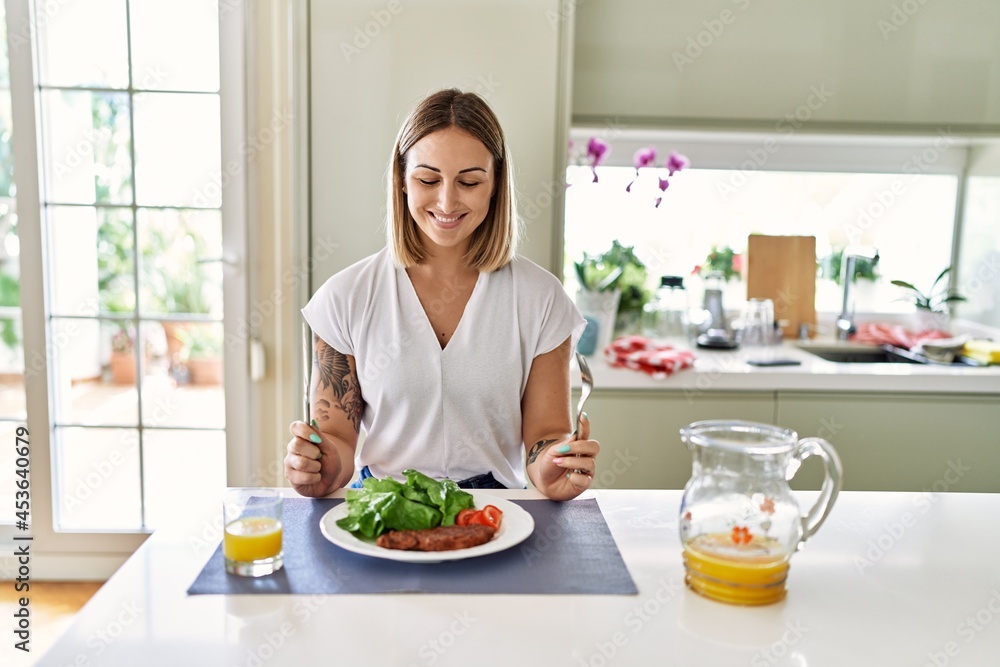 Young caucasian girl smiling happy having lunch at the kitchen.